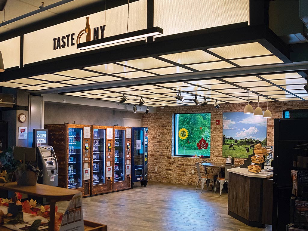 A small shop in the farmer's market with an ATM, vending machines, counter, and a small table and chairs