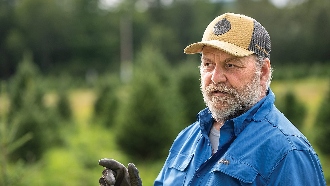 Close-up of a Christmas tree farmer with blurred background of trees.