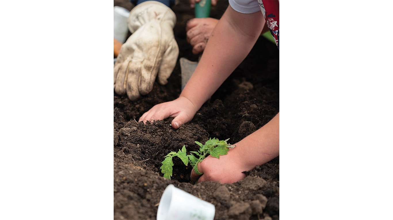 A child working soil to plant.