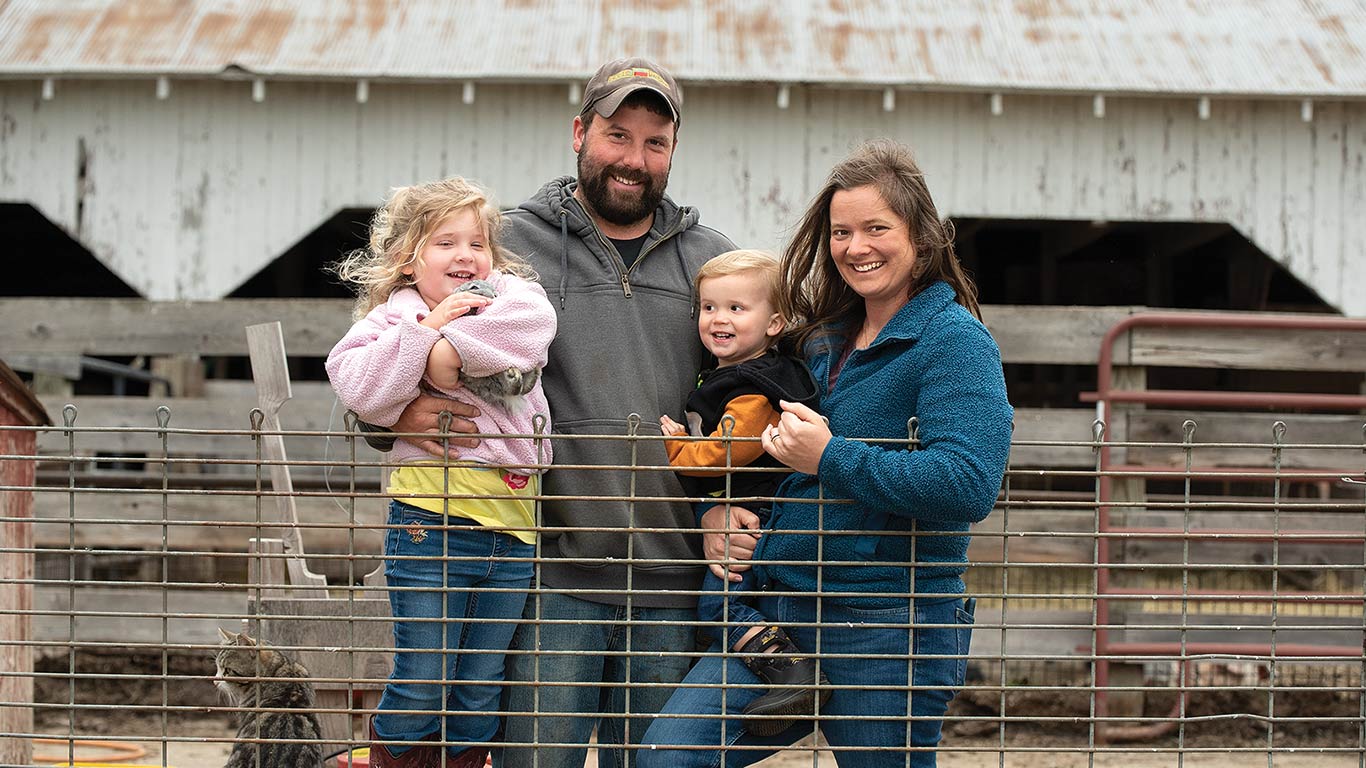A family posing with a barn in the background.
