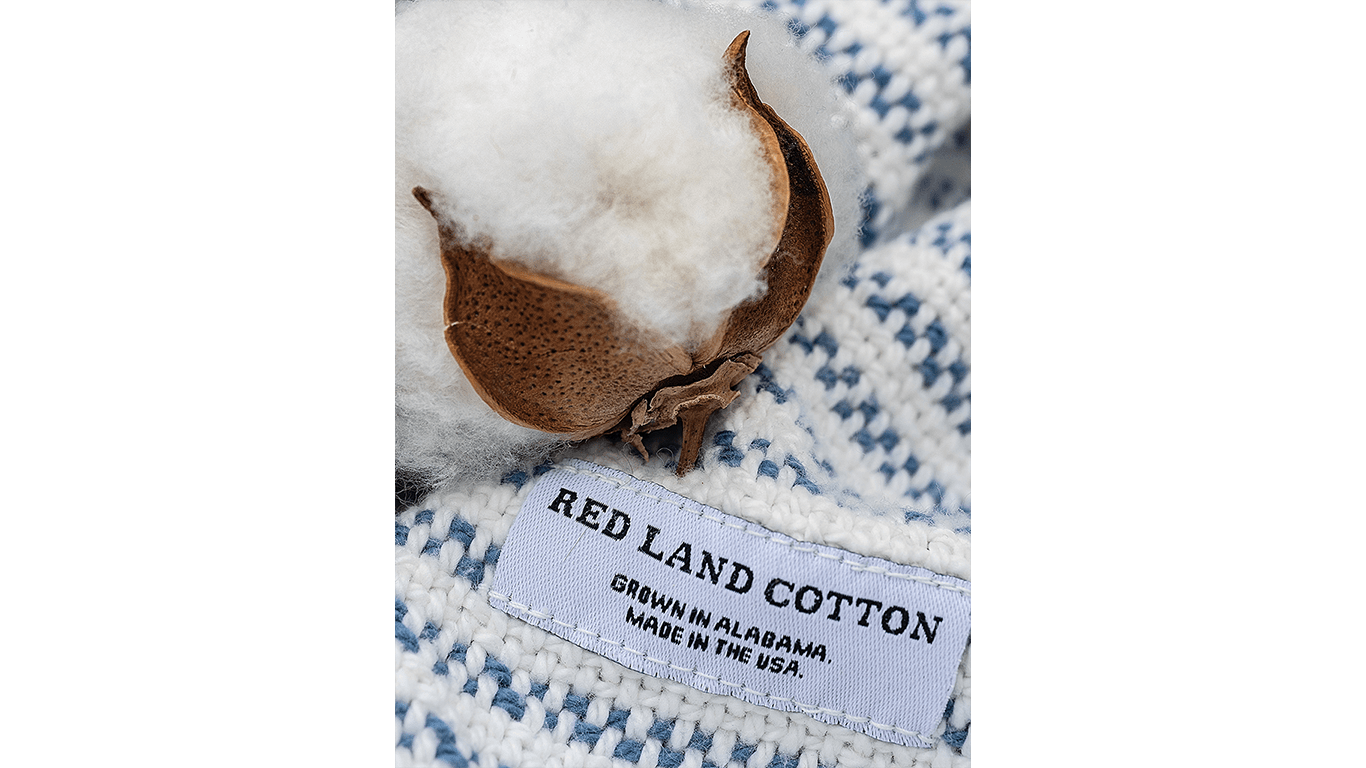 Cotton boll on blue-and-white woven fabric with tag reading "Red Land Cotton, Made in USA."