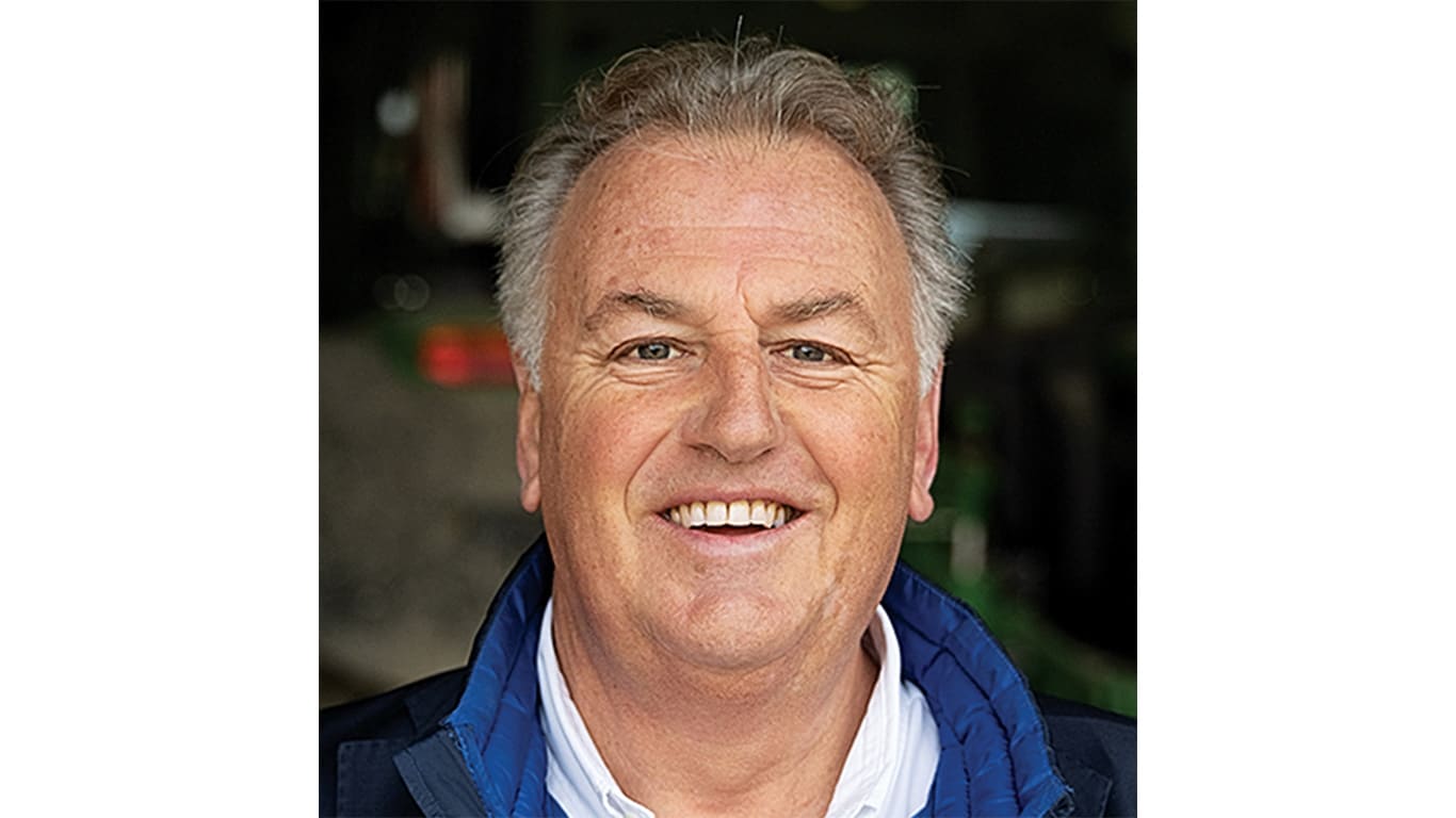 Person smiling wearing a white shirt and blue coat.