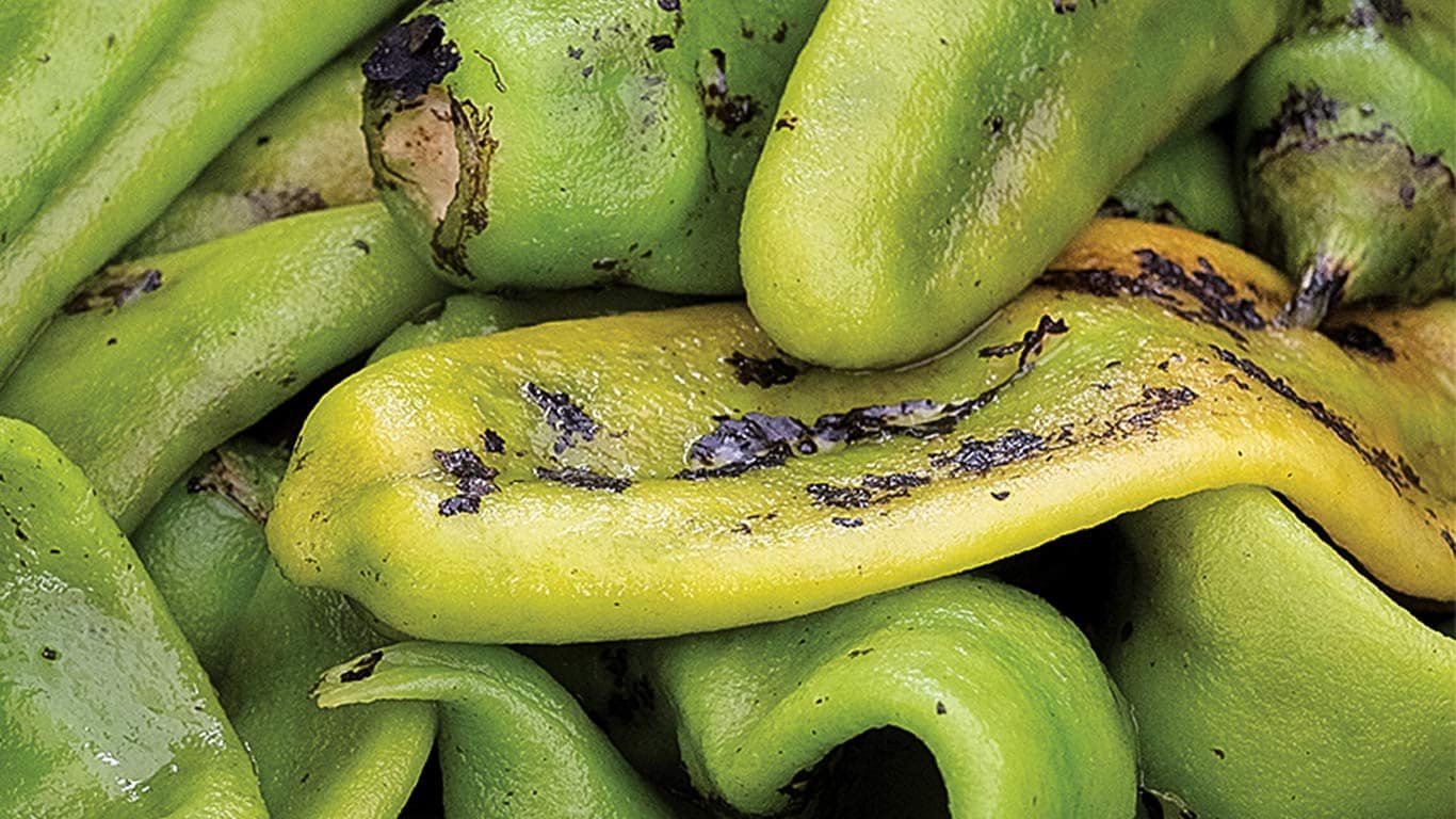 Close-up of green and yellow roasted peppers with charred spots.