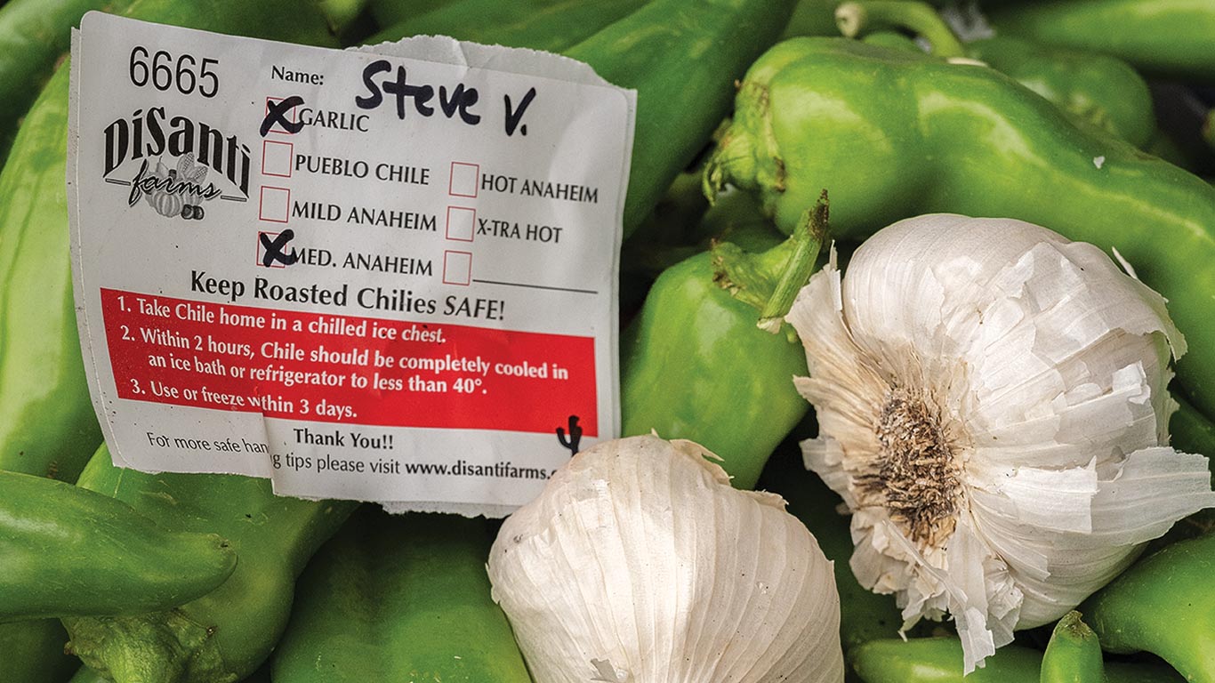 Green chilies and garlic bulbs with Disanti Farms label listing chili types and safety tips.