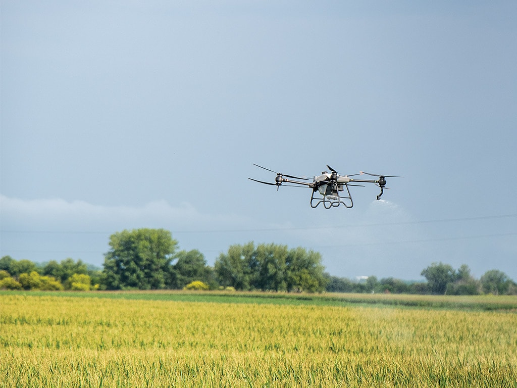A closeup of a drones spraying over a cornfield