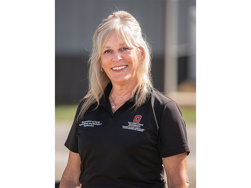 A closeup of a woman wearing a black polo shirt smiling.