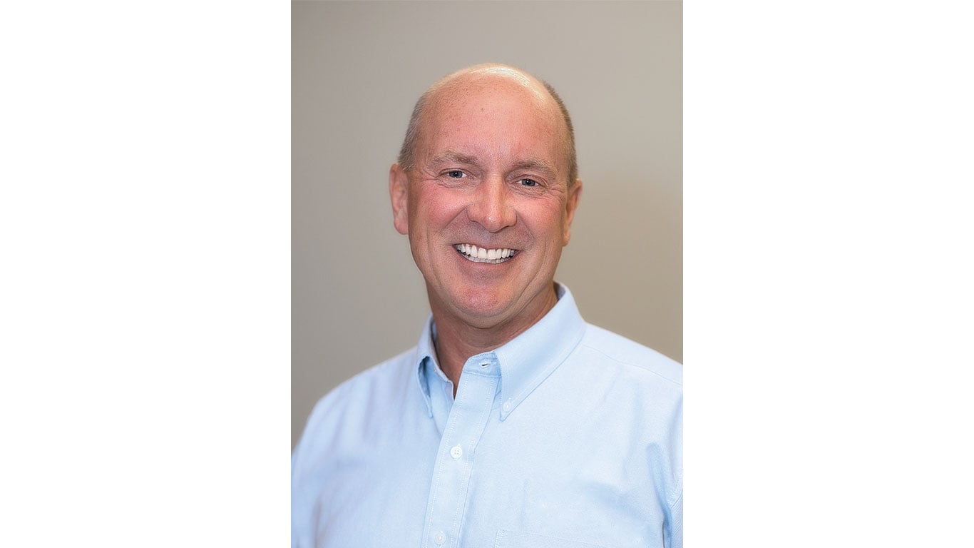 Smiling person in blue shirt against plain background
