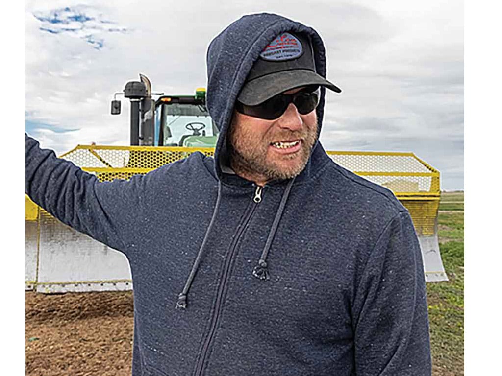 Colin Dammann standing in front of a piece of farm equipment