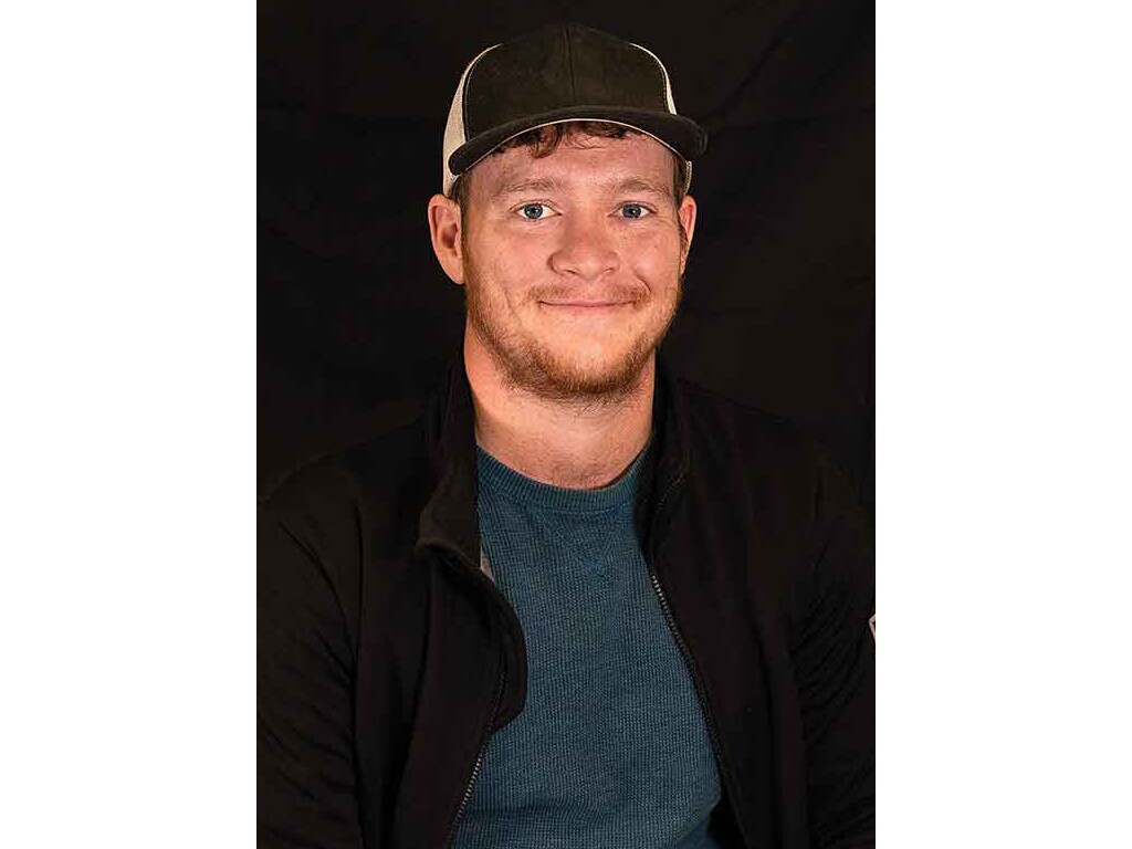 a headshot of a person in a baseball cap smiling