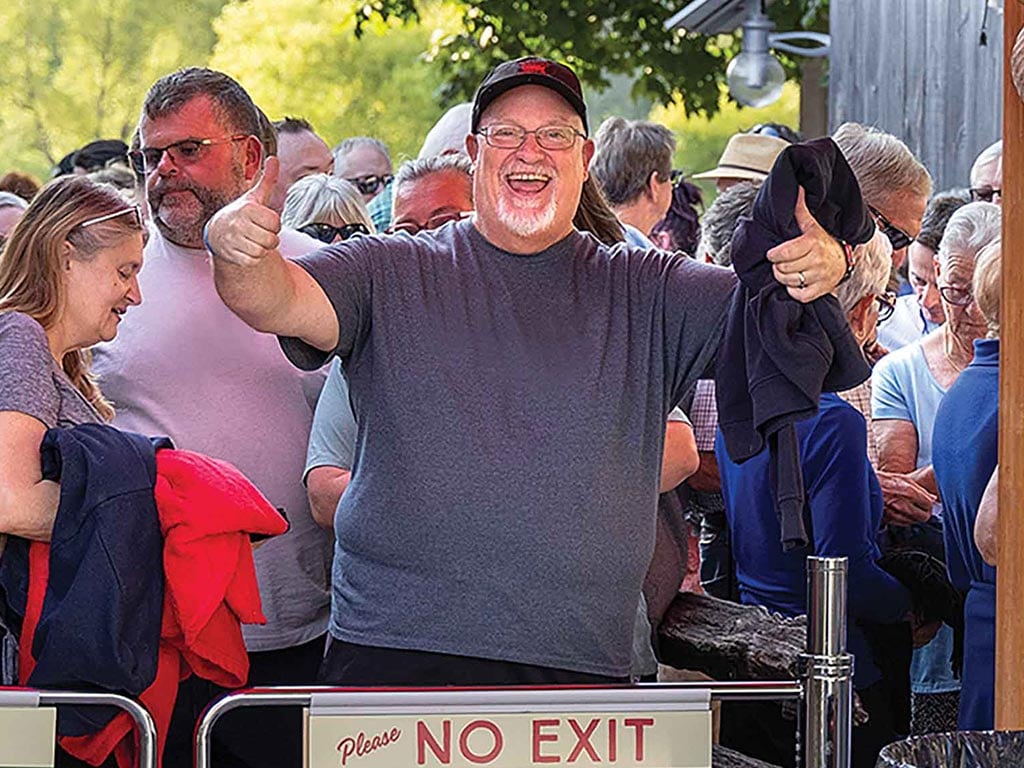 A crowd of people waits in line, with one person giving a thumbs up while holding clothing.