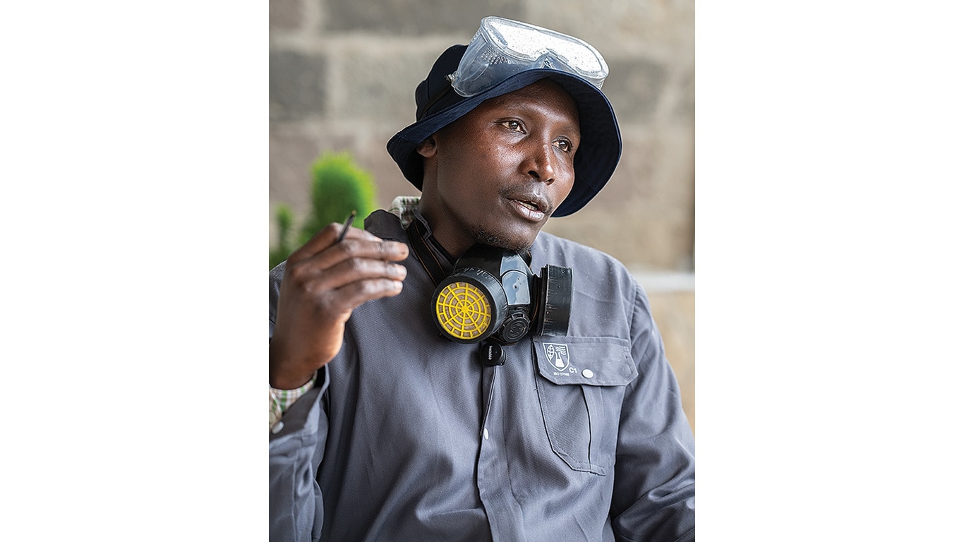 Farmer wearing protective goggles and respirator explains safe pesticide handling practices.