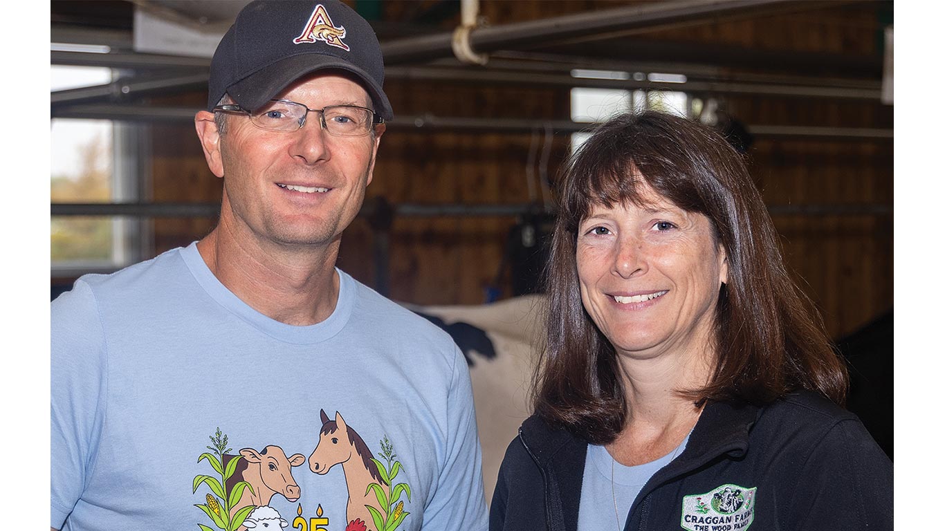 Two adults smile while standing together inside a barn.