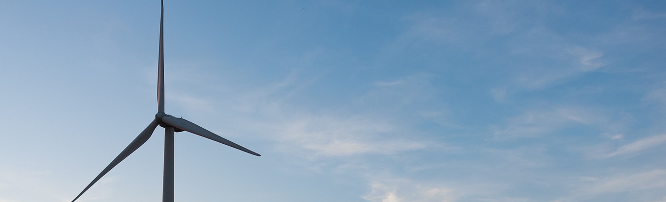 A wind turbine against a blue sky with light clouds.