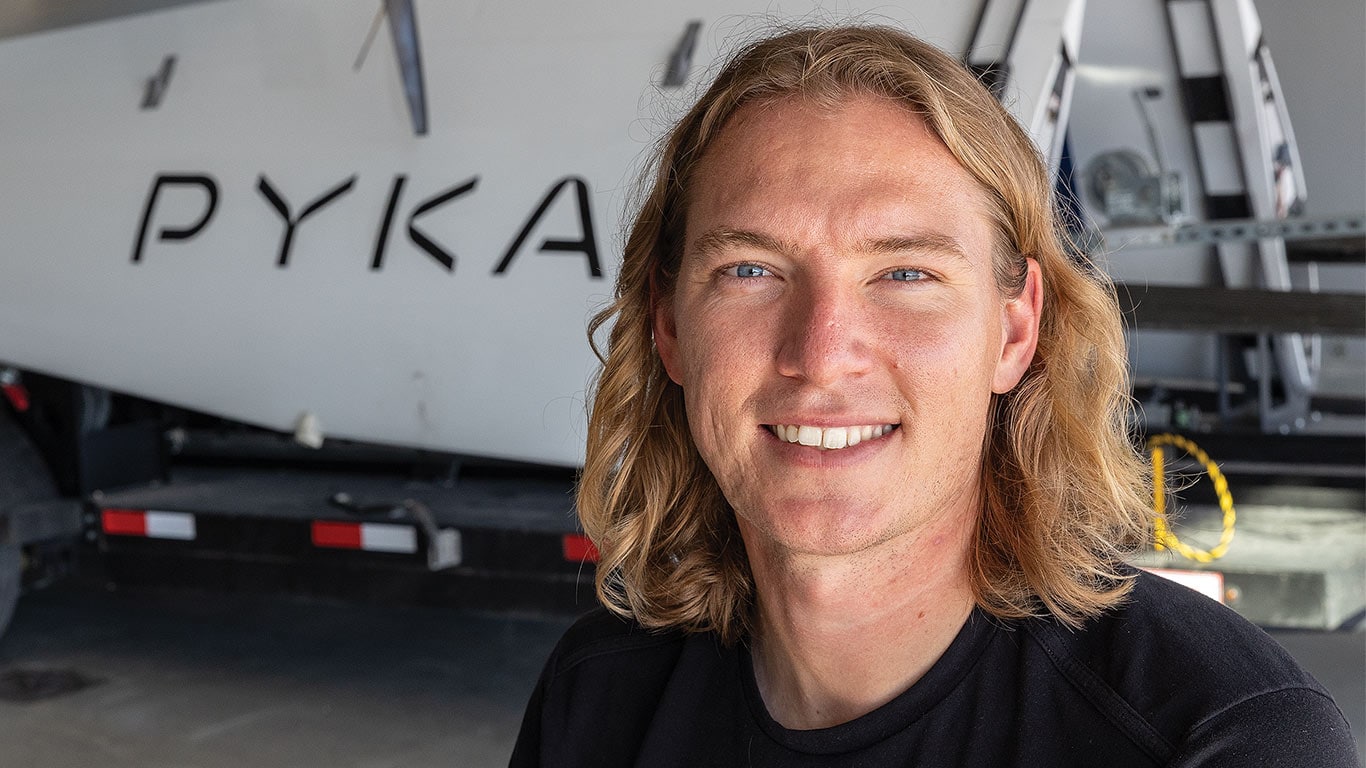 Person with blond hair standing in front of a PYKA aircraft inside a hangar.