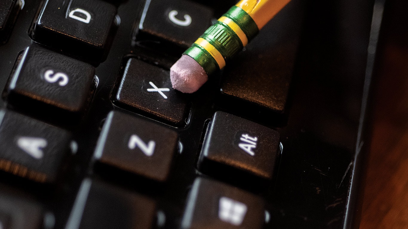 Pencil eraser resting on a keyboard key marked X.