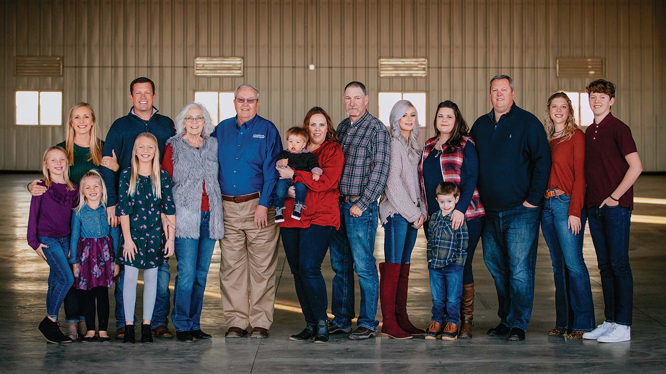 Large group of people standing together inside a spacious building with concrete floor.
