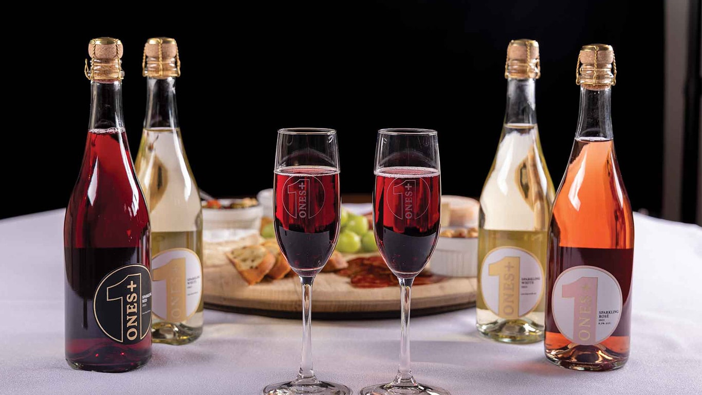 Bottles and glasses of sparkling beverages arranged on a table with a charcuterie board.