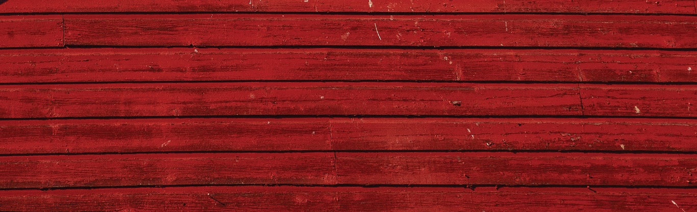 Close-up of weathered red painted wooden boards with visible grain and texture.