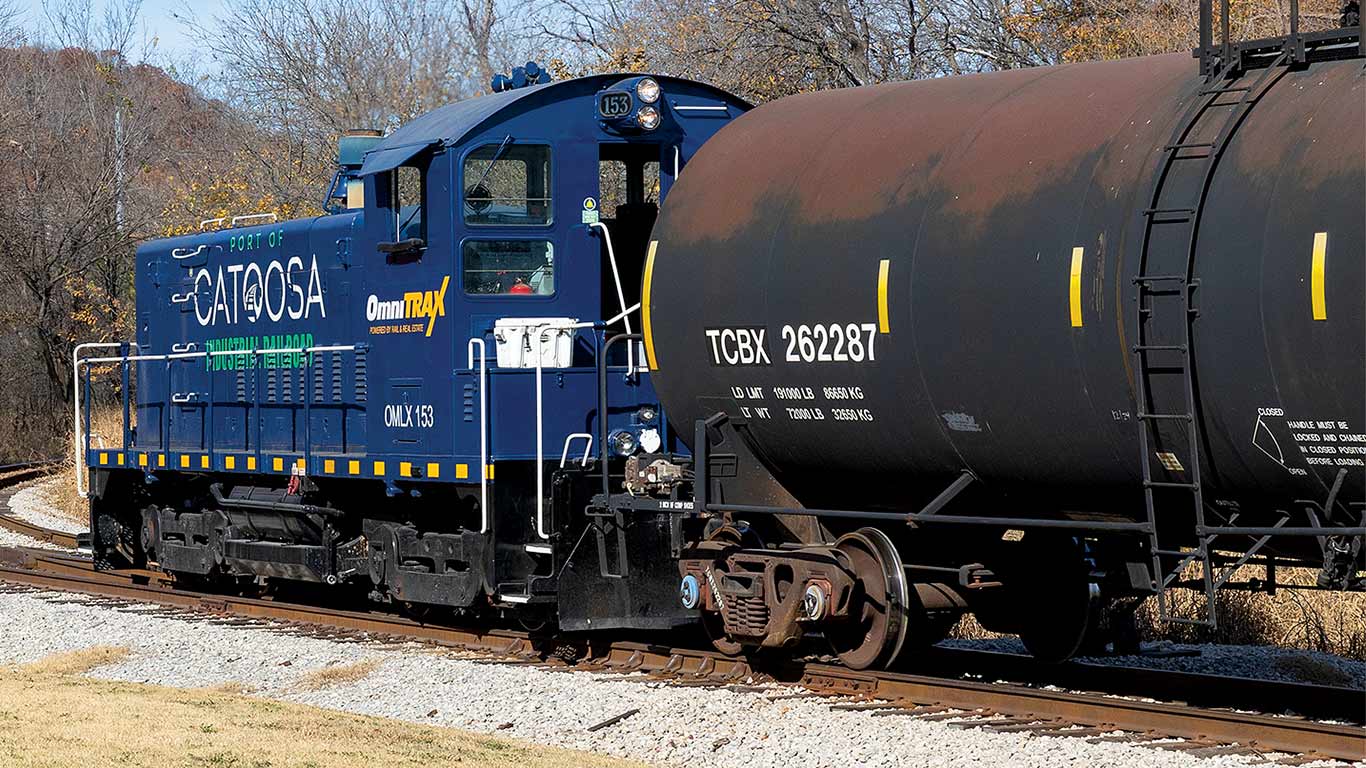 A blue train with tank car attached to it on railroad tracks.