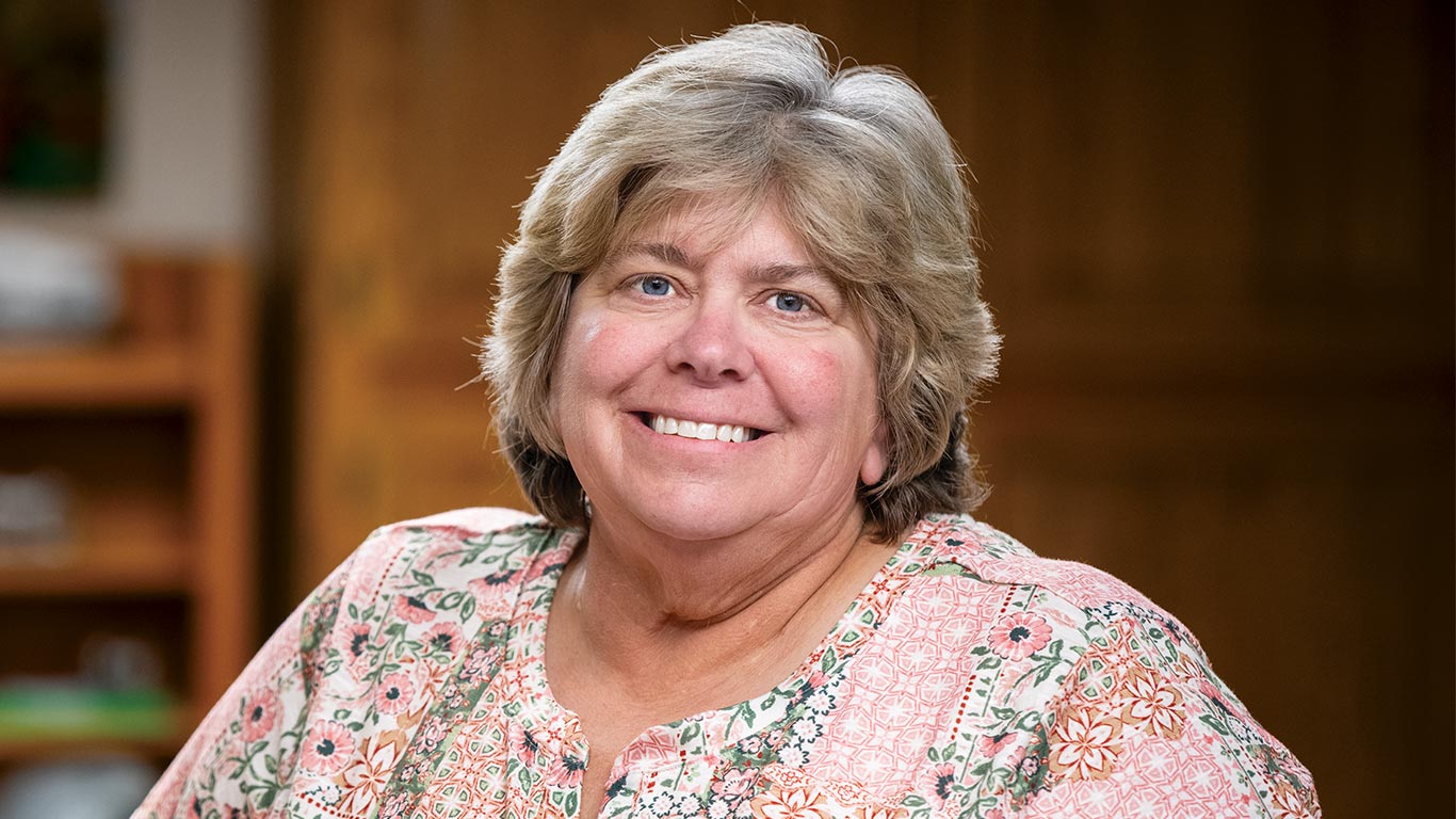 Close-up portrait of a person smiling indoors against a blurred background.