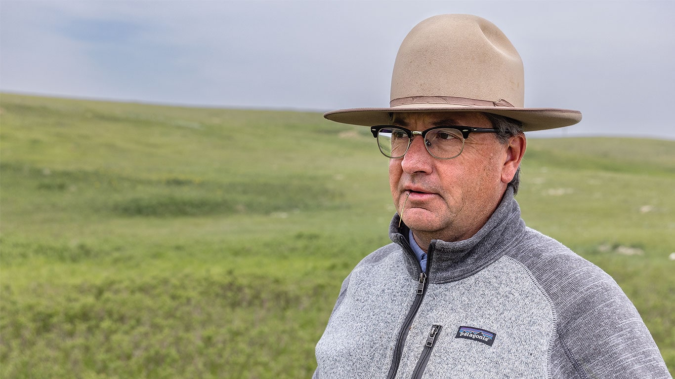 Individual with gallon hat standing in a open field with grey skies