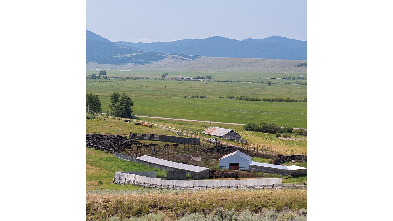 A long view of a valley with a cattle ranch in the foreground and mountains in the distance.