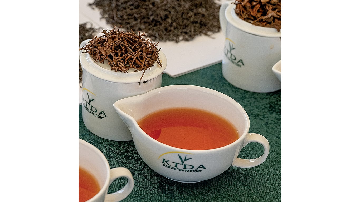 Cups of kenyan tea leaves curled and a cup of tea with KTDA logo on the cups.