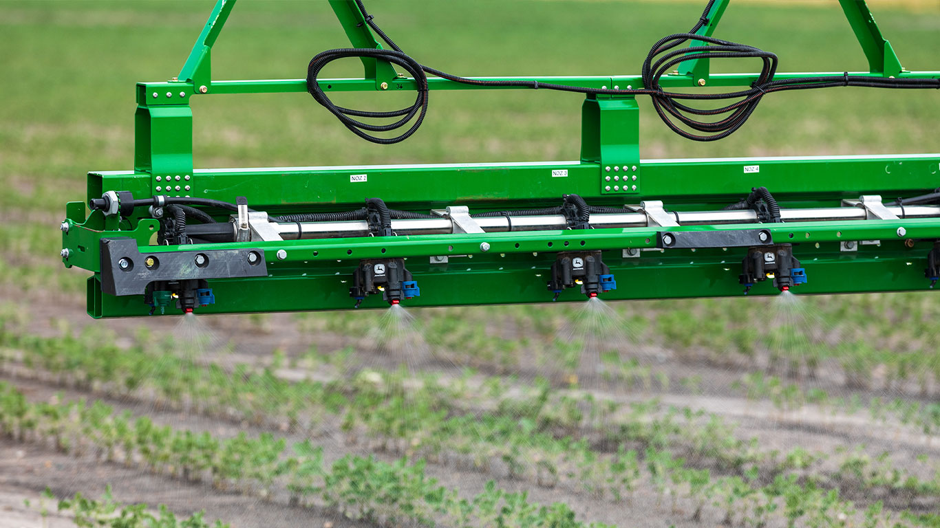 Photo of herbicide coming out of spray nozzle of self-propelled sprayer working in the field. 