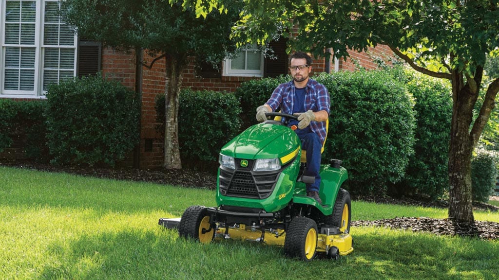 Man mowing front yard with lawn tractor