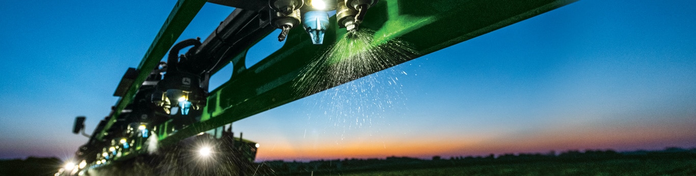 John Deere sprayer at work in the field at sunset