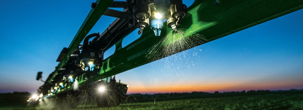 John Deere sprayer at work in the field at sunset